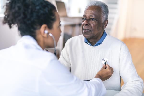 A doctor listening to the heartbeat of a senior man by using a stethoscope