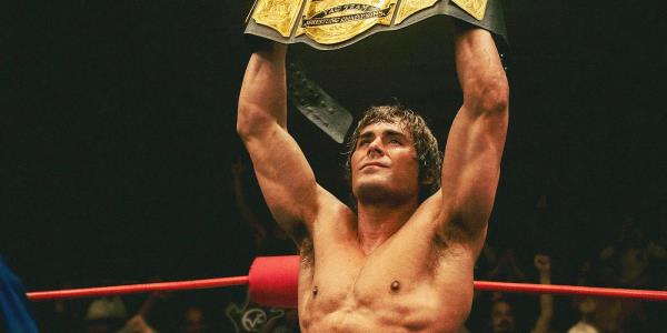 Zac Efron holding up a wrestling champion belt in The Iron Claw