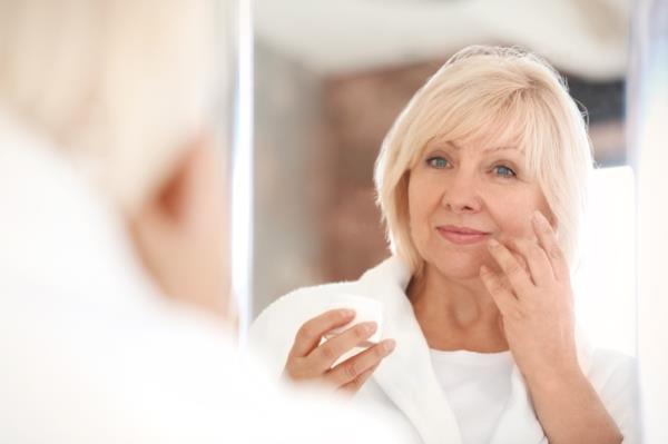 middle aged woman looking in a mirror, makeup for older women